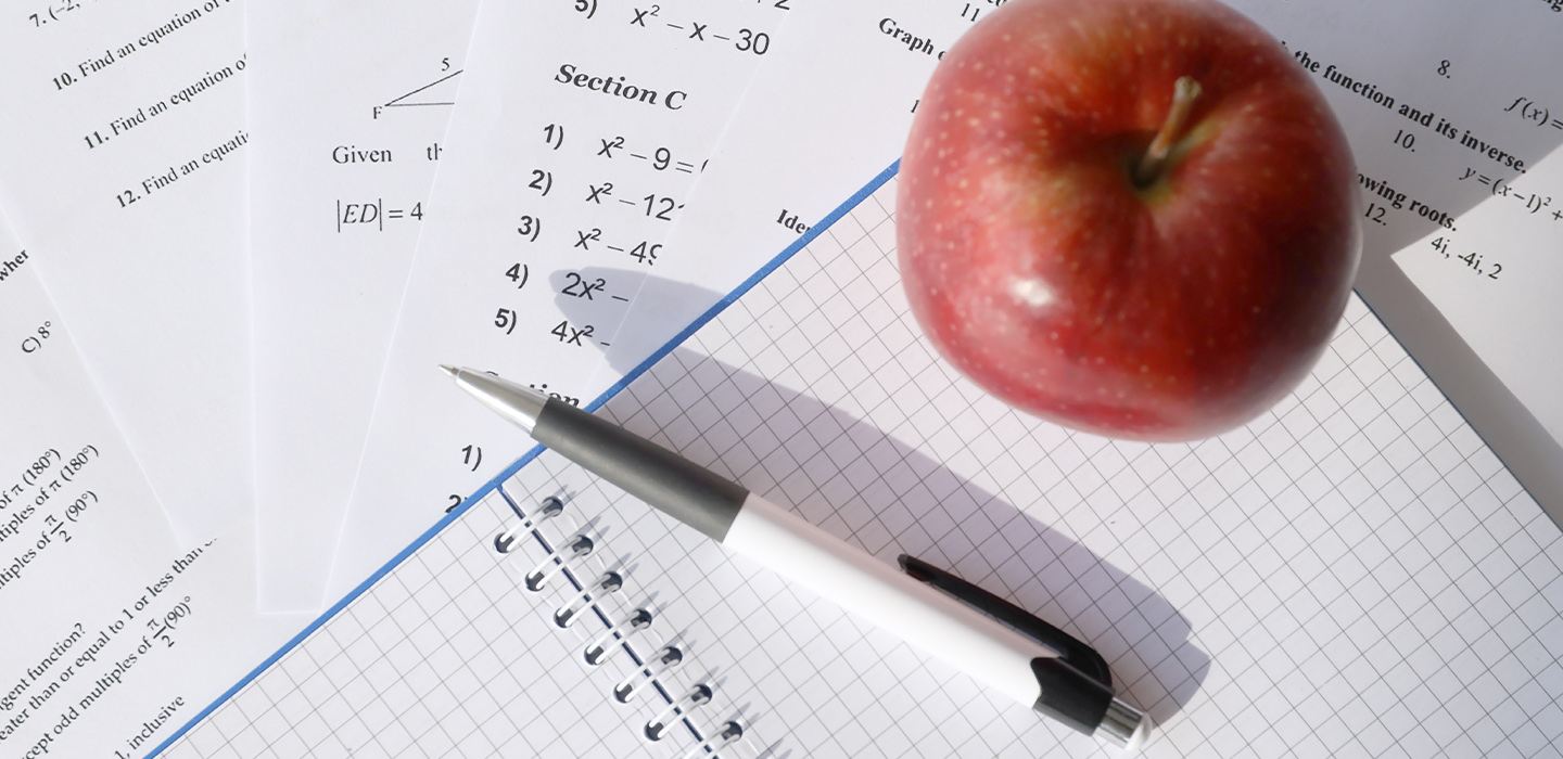 Math papers, apple and pen on desk