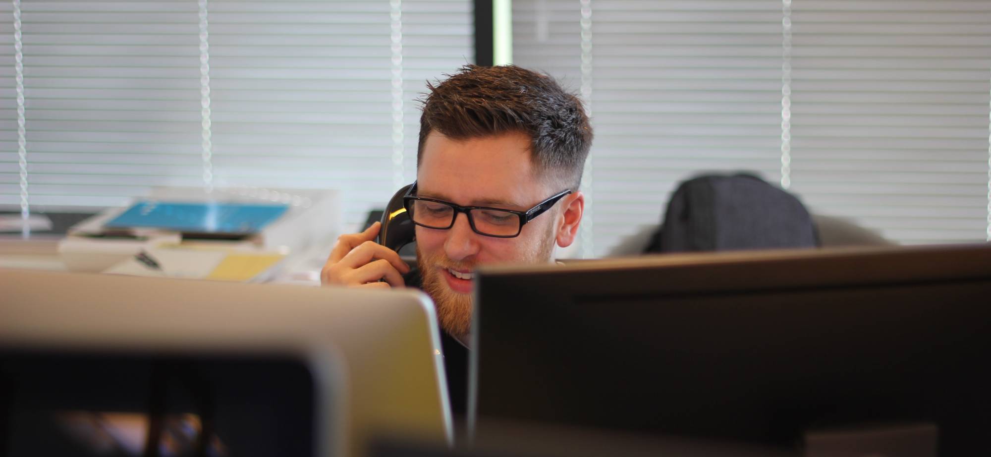 person on phone behind computer