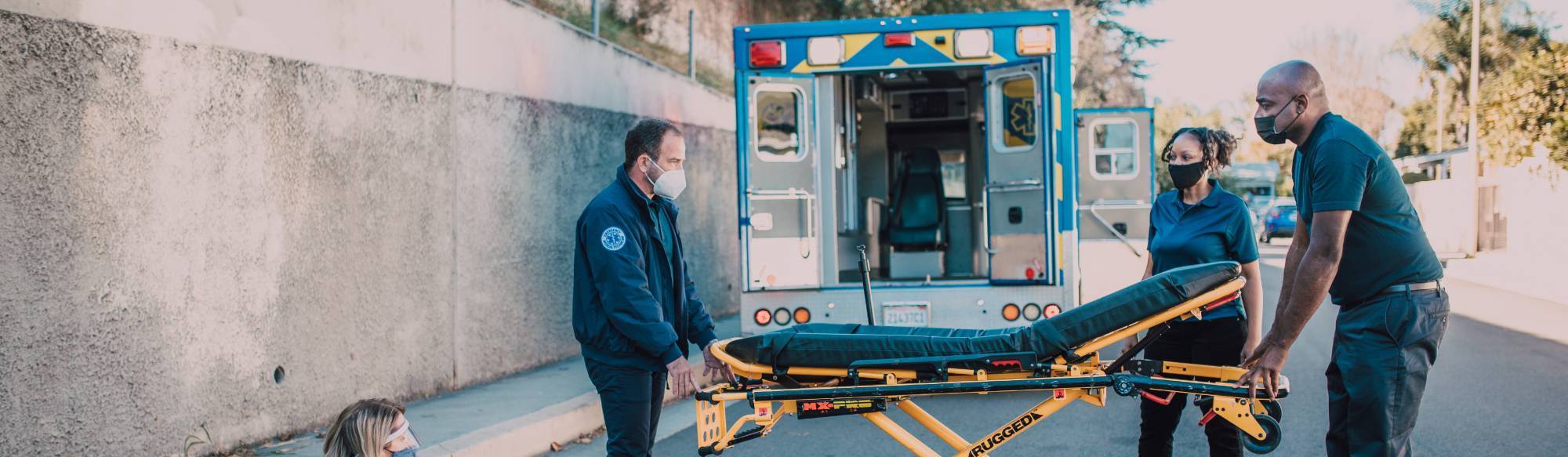 emergency medical persons with a stretcher outside on a road