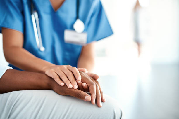 nurse in blue scrubs holding a persons hand