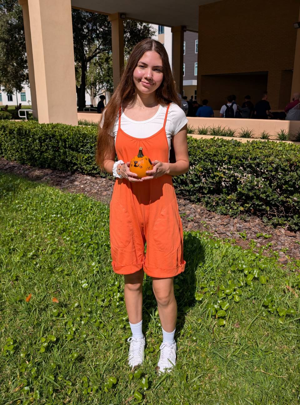 A student holding a small pumpkin at the Fall Fest. 