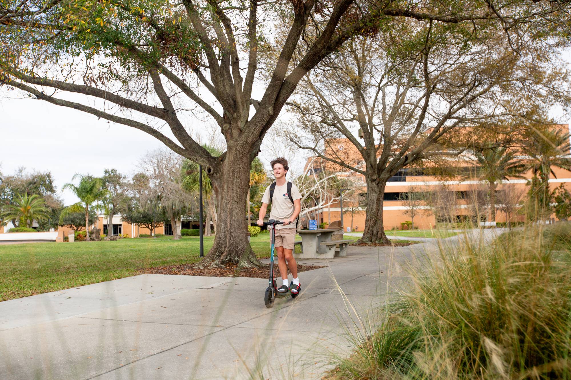 A student on a scooter riding across campus.