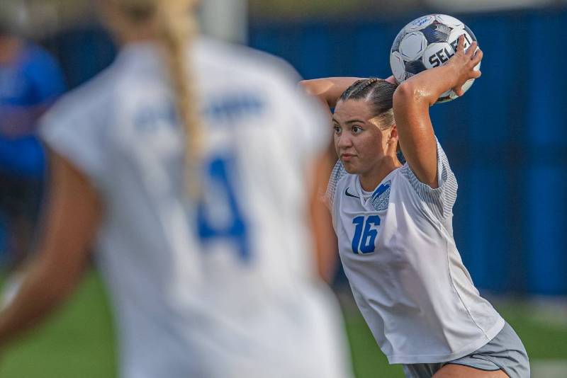 A Falcon student-athlete throwing the ball into play during a women's soccer match. 
