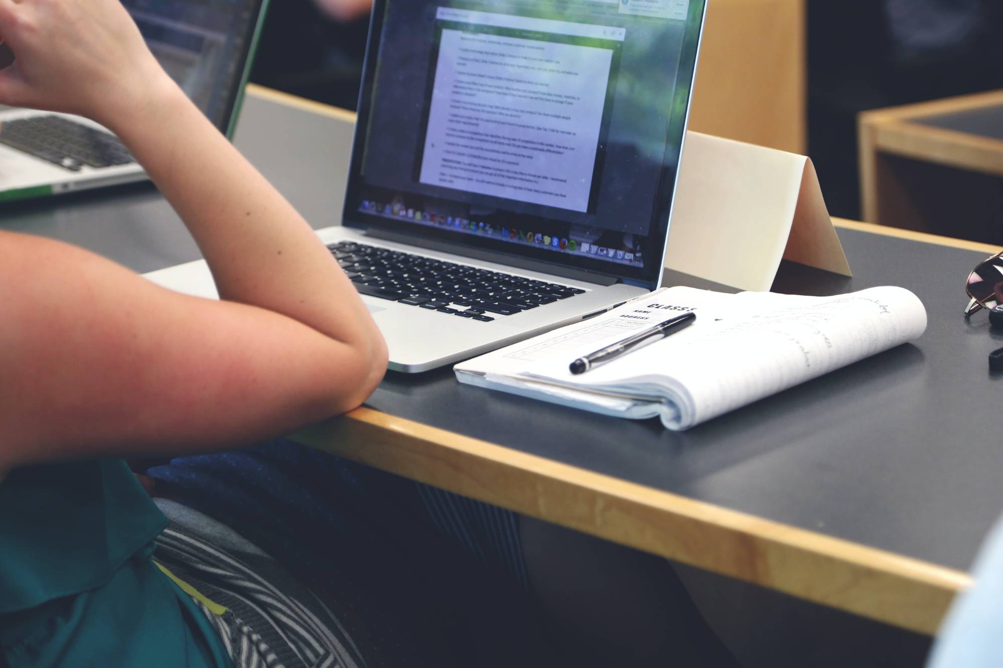 person in classroom with laptop and notebook